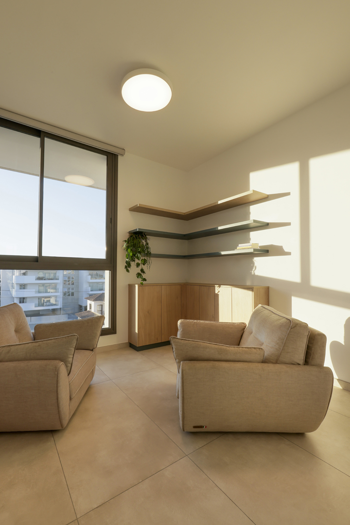Psychologist office consultation room by KK Interior Design with lounge chairs, corner shelving, natural light, and minimalist wood cabinetry