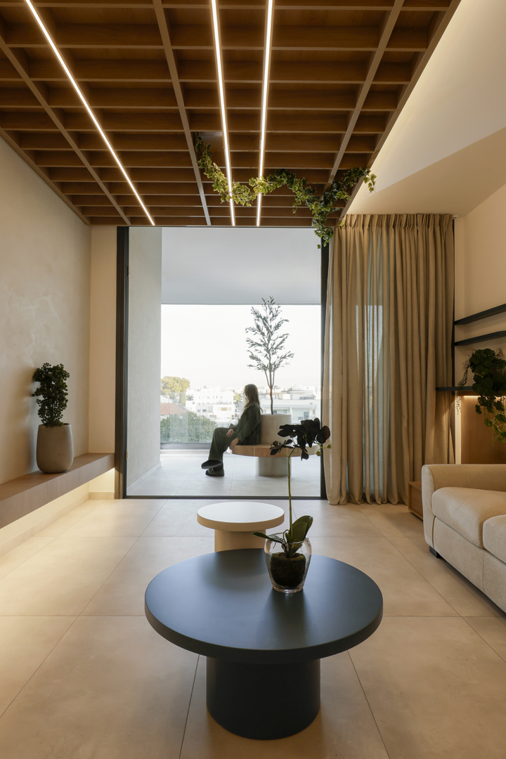 Modern psychologist office interior by KK Interior Design with ceiling grid lighting, indoor plants, curtain partition, and view toward outdoor seating