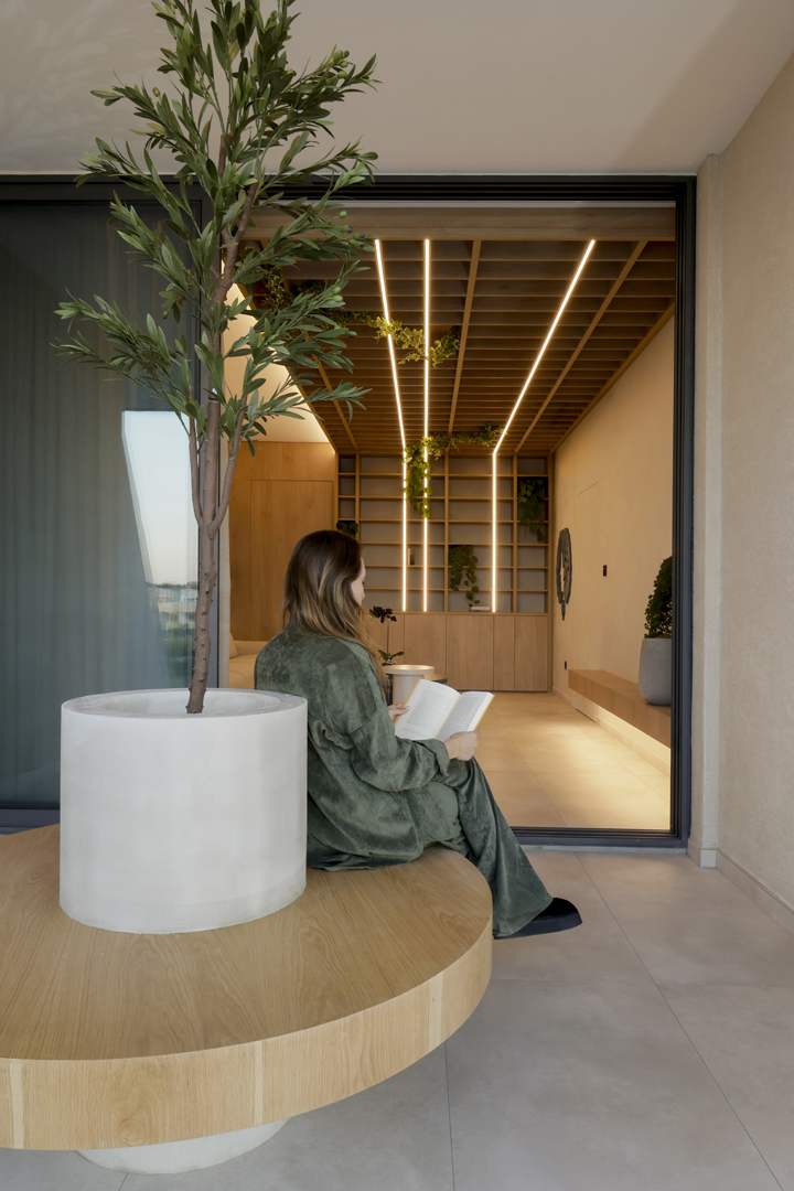 Psychologist office terrace connection by KK Interior Design with indoor-outdoor transition, wood ceiling grid, plants, and seating visible through glass