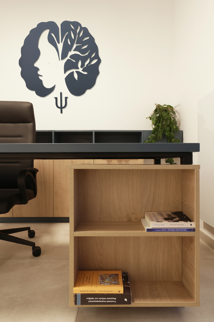 Close-up of psychologist office desk storage by KK Interior Design with open shelving and books beneath work surface