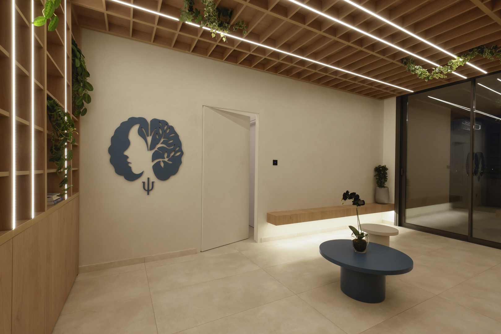 Psychologist office waiting area by KK Interior Design with concealed doorway, floating bench, shelving wall, and integrated ceiling lighting