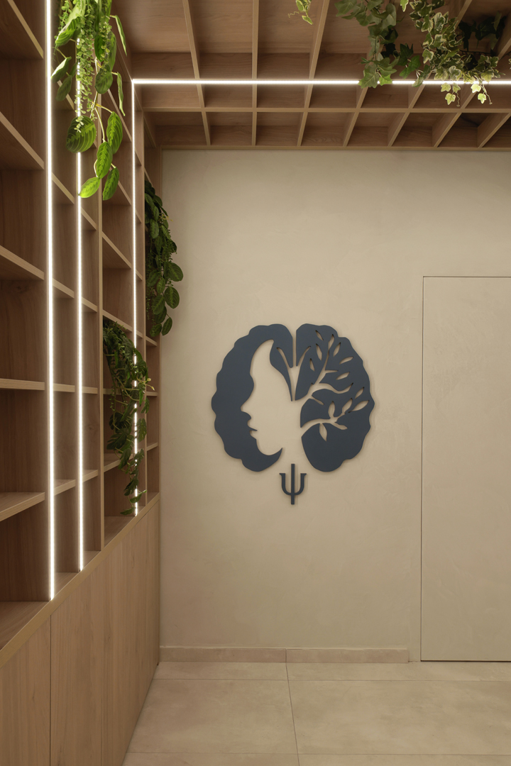 Psychologist office interior detail by KK Interior Design highlighting wall emblem, shelving, and wood ceiling grid with LED lighting