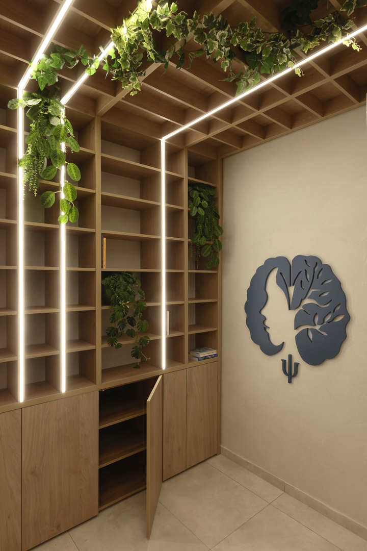 Custom shelving wall in psychologist office by KK Interior Design with integrated vertical lighting, indoor plants, and wood cabinetry
